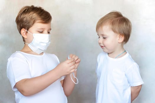 The older brother puts on a medical mask for his younger brother. Coronavirus, disease, infection, quarantine, medical mask, COVID-19. Quarantine and protection from influenza viruses and epidemics covid-19. Coronavirus quarantine.