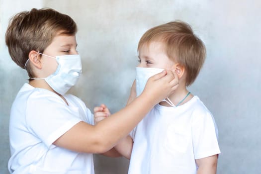 The older brother puts on a medical mask for his younger brother. Coronavirus, disease, infection, quarantine, medical mask, COVID-19. Quarantine and protection from influenza viruses and epidemics covid-19. Coronavirus quarantine.