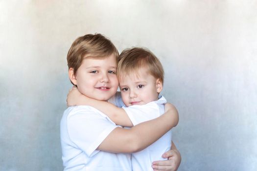 Boys-brothers in an embrace. Happy boys hug each other. Overjoyed, the best friends embrace. The true concept of a strong friendship.