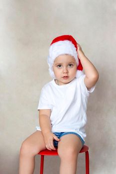 Portrait of a cute little boy in a white t-shirt and Santa Claus hat. Children's emotions. Christmas and new year. Success, bright idea, creative ideas and concepts. The concept of an advertising banner.