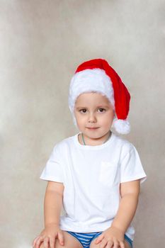 Portrait of a cute little boy in a white t-shirt and Santa Claus hat. Children's emotions. Christmas and new year. Success, bright idea, creative ideas and concepts. The concept of an advertising banner.