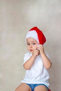 Portrait of a cute little boy in a white t-shirt and Santa Claus hat. Children's emotions. Christmas and new year. Success, bright idea, creative ideas and concepts. The concept of an advertising banner. 