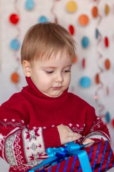 Portrait of a cute boy near the Christmas tree with gifts in his hands. Children's emotions. Christmas and new year. The concept of an advertising banner. 