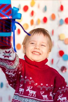 Portrait of a cute boy with a gift in his hands. Children's emotions. Christmas and new year. The concept of an advertising banner.