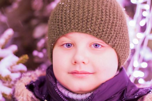 Portrait of a boy in the light of iridescent lights. Christmas in the city. illuminated decorations close-up. Photo