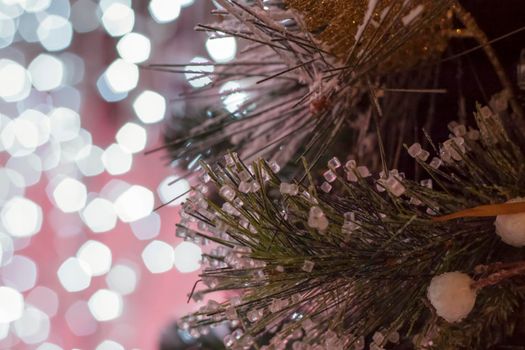 Christmas and New Year holiday background. Close-up of a Christmas tree in the snow against a background of bright lights. Snow