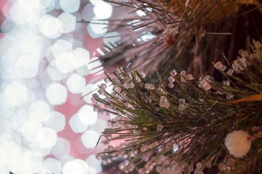 Christmas and New Year holiday background. Close-up of a Christmas tree in the snow against a background of bright lights. Snow