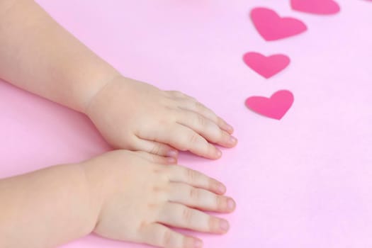 Children's hands on a pink background with hearts. The concept of the Valentine's Day theme. A greeting card, a declaration of love. February 14