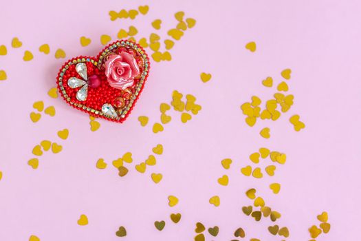 Pink background with gold hearts, sequins. Red heart made of beads. The concept of the Valentine's Day theme. Postcard, template, background for graphic works. The concept of the Valentine's Day theme. February 14