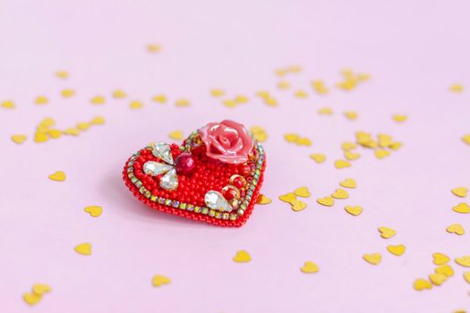 Pink background with gold hearts, sequins. Red heart made of beads. The concept of the Valentine's Day theme. Postcard, template, background for graphic works. The concept of the Valentine's Day theme. February 14 