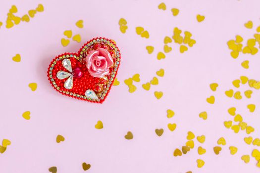 Pink background with gold hearts, sequins. Red heart made of beads. The concept of the Valentine's Day theme. Postcard, template, background for graphic works. The concept of the Valentine's Day theme. February 14