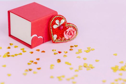 Pink background with gold hearts, sequins. Red heart made of beads. The concept of the Valentine's Day theme. Postcard, template, background for graphic works. The concept of the Valentine's Day theme. February 14