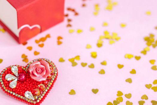 Pink background with gold hearts, sequins. Red heart made of beads. The concept of the Valentine's Day theme. Postcard, template, background for graphic works. The concept of the Valentine's Day theme. February 14 