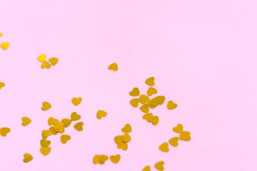 Pink background with gold hearts, sequins. The concept of the Valentine's Day theme. Postcard, template, background for graphic works.