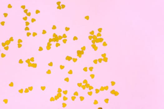 Pink background with gold hearts, sequins. The concept of the Valentine's Day theme. Postcard, template, background for graphic works.