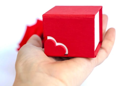 Red box for decoration with a heart on the palm. The concept of the Valentine's Day theme. A greeting card, a declaration of love. February 14