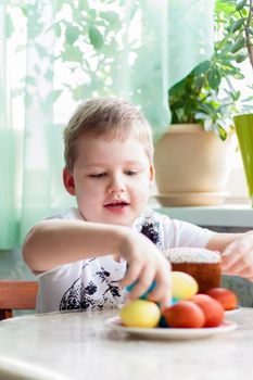 Portrait of a cute child with Easter eggs. Easter lunch. The feast of Holy Easter. Painted Easter eggs.