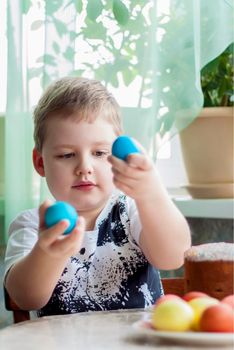 Portrait of a cute child with Easter eggs. Easter lunch. The feast of Holy Easter. Painted Easter eggs.