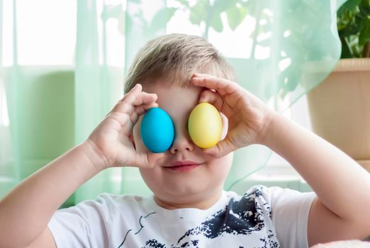 Portrait of a cute child with Easter eggs. Easter lunch. The feast of Holy Easter. Painted Easter eggs.