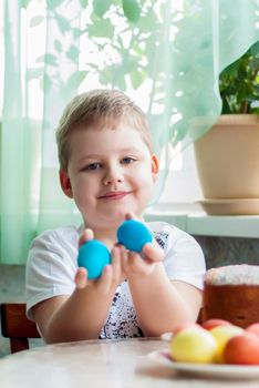 Portrait of a cute child with Easter eggs. Easter lunch. The feast of Holy Easter. Painted Easter eggs.