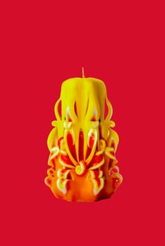 Bright yellow carved candle on a red background. Background for a Christmas card. Valentine's day. Background for advertising and business. Christmas, New year, Valentine's Day