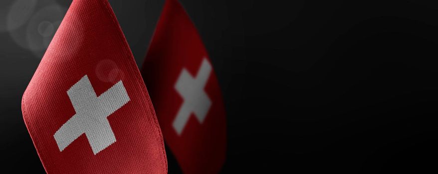 Small national flags of the Switzerland on a dark background.