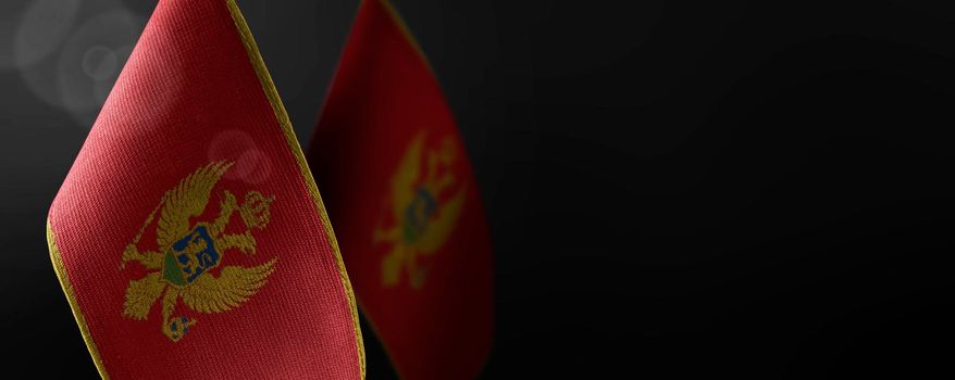 Small national flags of the Montenegro on a dark background.
