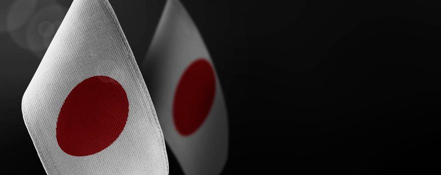 Small national flags of the Japan on a dark background.