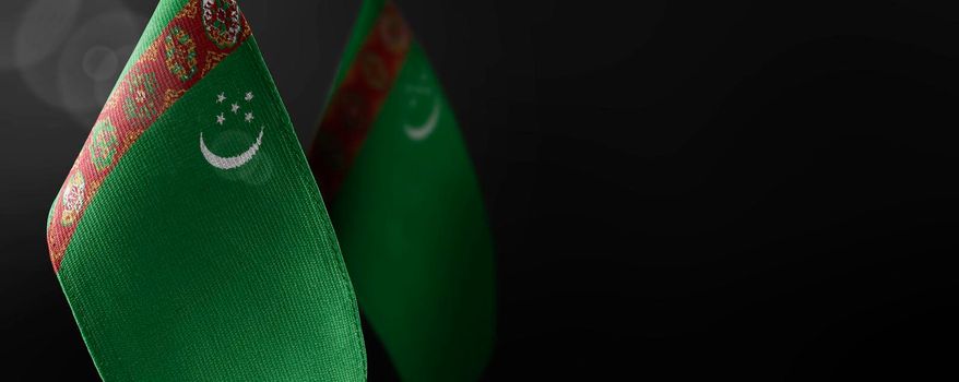 Small national flags of the Turkmenistan on a dark background.