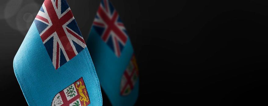 Small national flags of the Fiji on a dark background.