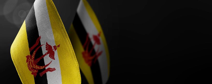 Small national flags of the Brunei on a dark background.