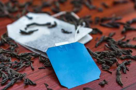A new tea bag with a label close-up lies on the leaves of a large-leaved black tea