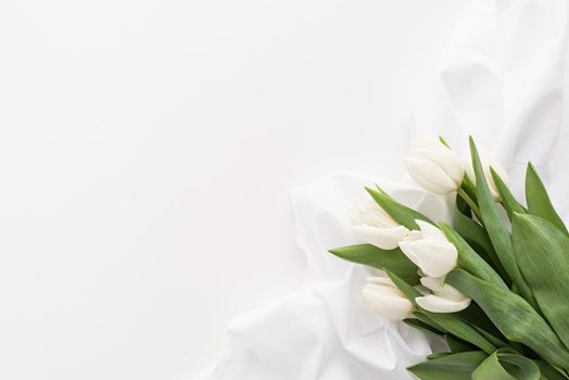 Spring concept. White tulip bouquet and fabric for mock up design on white background with copy space