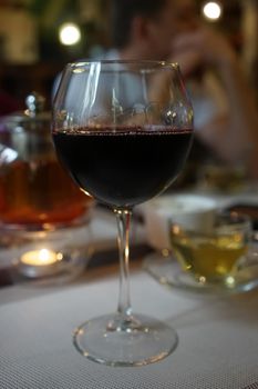 A glass of wine on a blurred background with people.