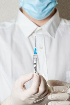 Doctor holding a syringe with a vaccine against coronavirus infection, the concept of universal mass vaccination