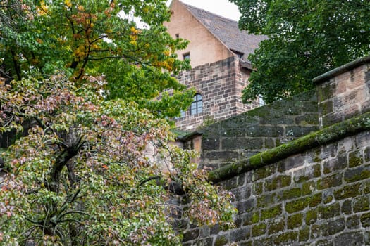 Historic wall and building of the Nuremberg castle, Bavaria, Germany  in autunm with multicolored tree in the foreground