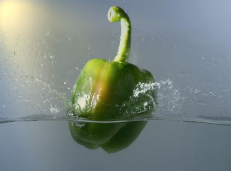 Vintage green bell peppers thrown into the water with a splash of water.