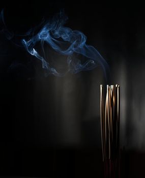 Burning incense, white smoke, black background, used as a worship background image, a sacred object of Buddhist beliefs, focus on the smoke.