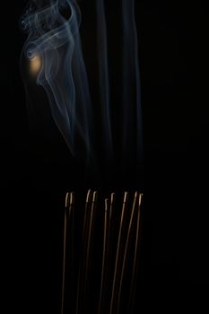 Incense burning incense, white smoke, black background, used as background image Paying homage to the sacred objects of the people of Buddhism according to their beliefs and beliefs.