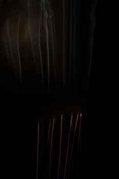 Incense burning incense, white smoke, black background, used as background image Paying homage to the sacred objects of the people of Buddhism according to their beliefs and beliefs.