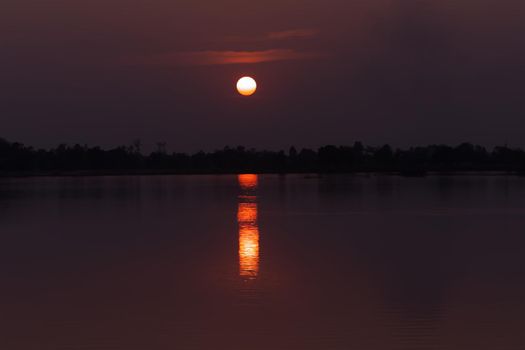 The scenery along the lake has an orange sky and a beautiful sunset.