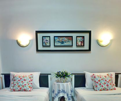 The luxurious twin bedroom features white linens and floral pillowcases.