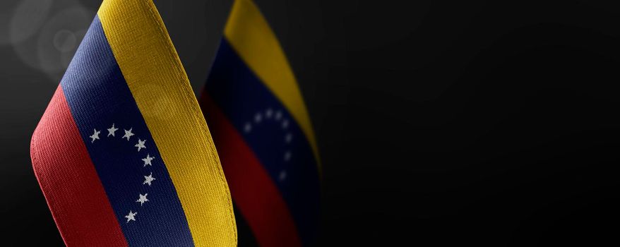 Small national flags of the Venezuela on a dark background.