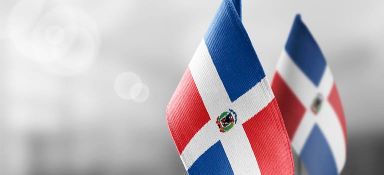 Small national flags of the Dominicana on a light blurry background.