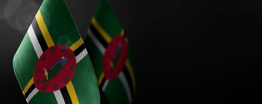 Small national flags of the Dominica on a dark background.