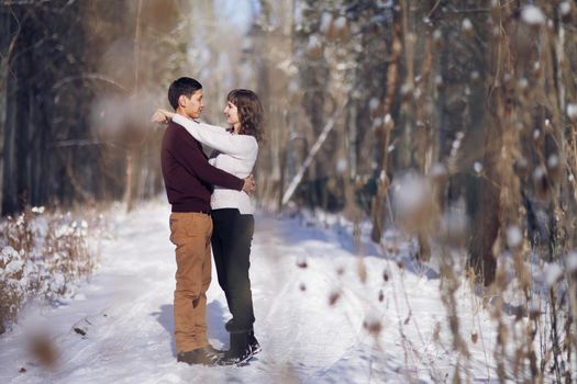 Young couple hug each other in winter in the park. Love story
