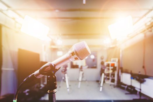 Professional microphone in recording tv studio, studio lights in blurry background