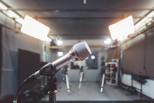 Professional microphone in recording tv studio, studio lights in blurry background