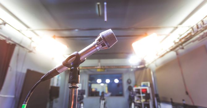 Professional microphone in recording tv studio, studio lights in blurry background