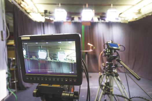 Film camera on a tripod in a television broadcasting studio, spotlights and equipment